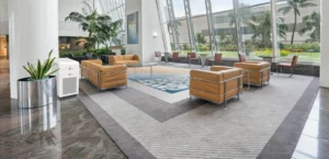 Spacious lobby with tan leather chairs, large windows, potted plants, and a white air purifier next to a large column.